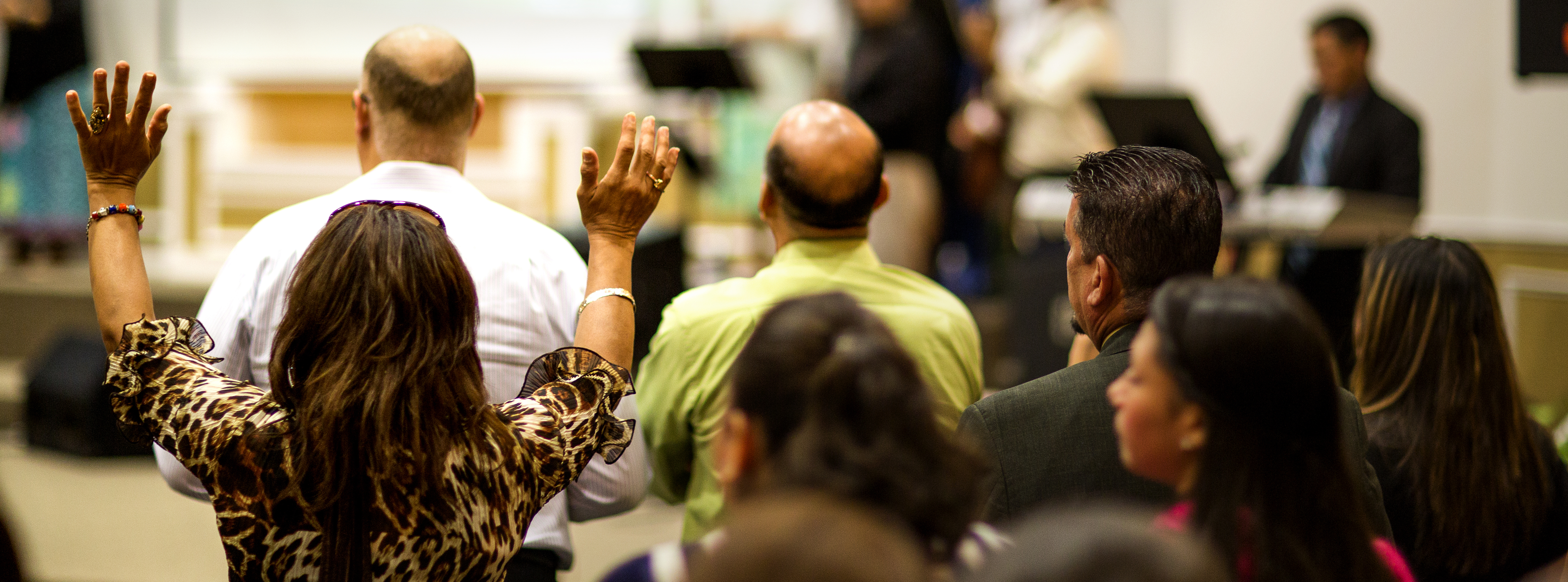 A Latina congregational member of Ark of Salvation raises her hands in worship. 